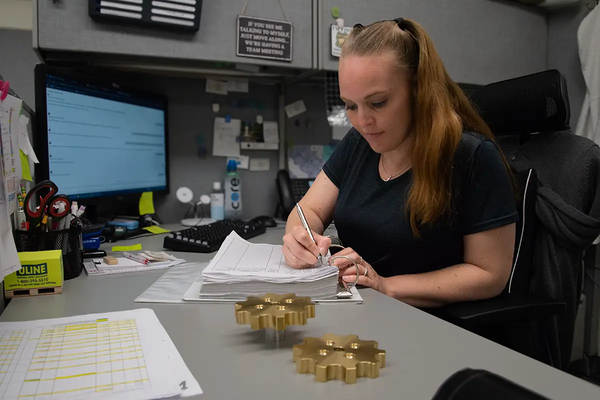 DTS Purchasing Heather at Computer with Parts on Desk