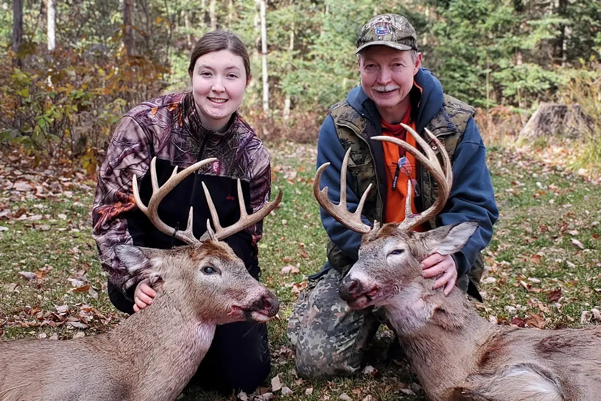 DTS Employee with family member on ground holding Deer Bucks by the antlers